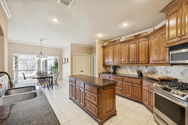 a kitchen with stainless steel appliances granite countertop a stove top oven a sink dishwasher a dining table and chairs with wooden floor