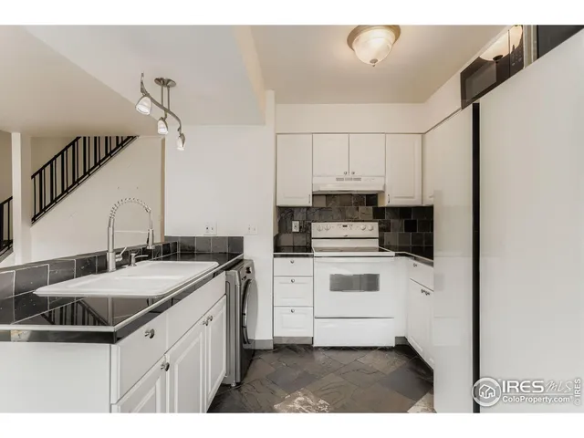 a kitchen with kitchen island a sink cabinets and white appliances