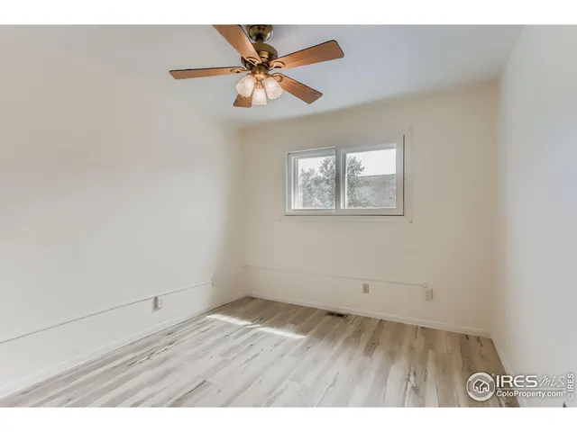 an empty room with wooden floor and ceiling fan