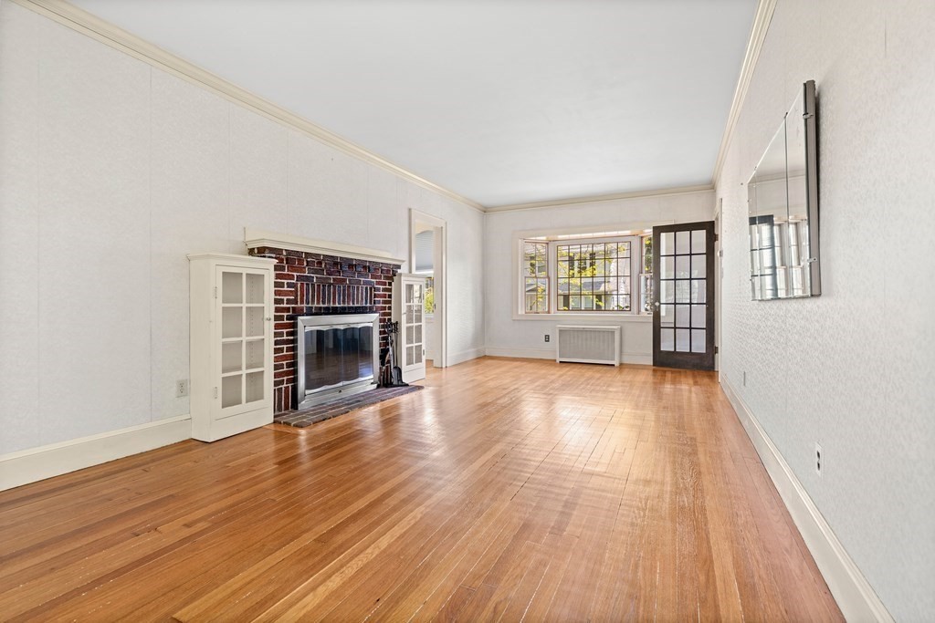 61 Waldeck Road Milton, MA 02186 - Photo 11 of 31 an empty room with wooden floor and fireplace