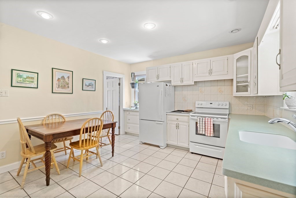61 Waldeck Road Milton, MA 02186 - Photo 7 of 31 a kitchen with a dining table chairs and white appliances