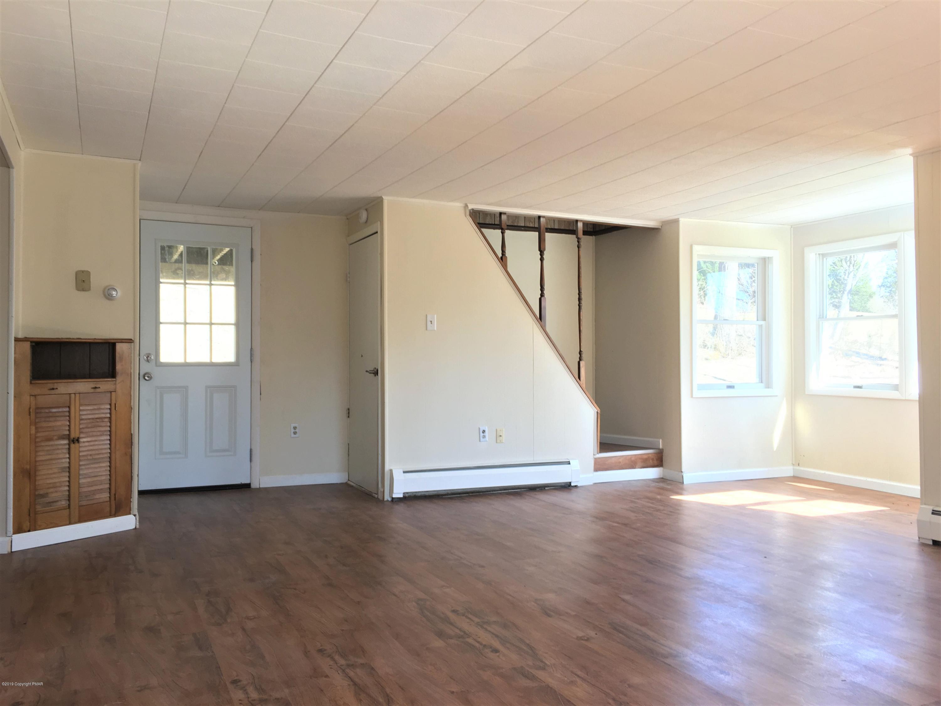 5736 Neola Road Stroudsburg, PA 18360 - Photo 14 of 37 an empty room with wooden floor staircase and windows