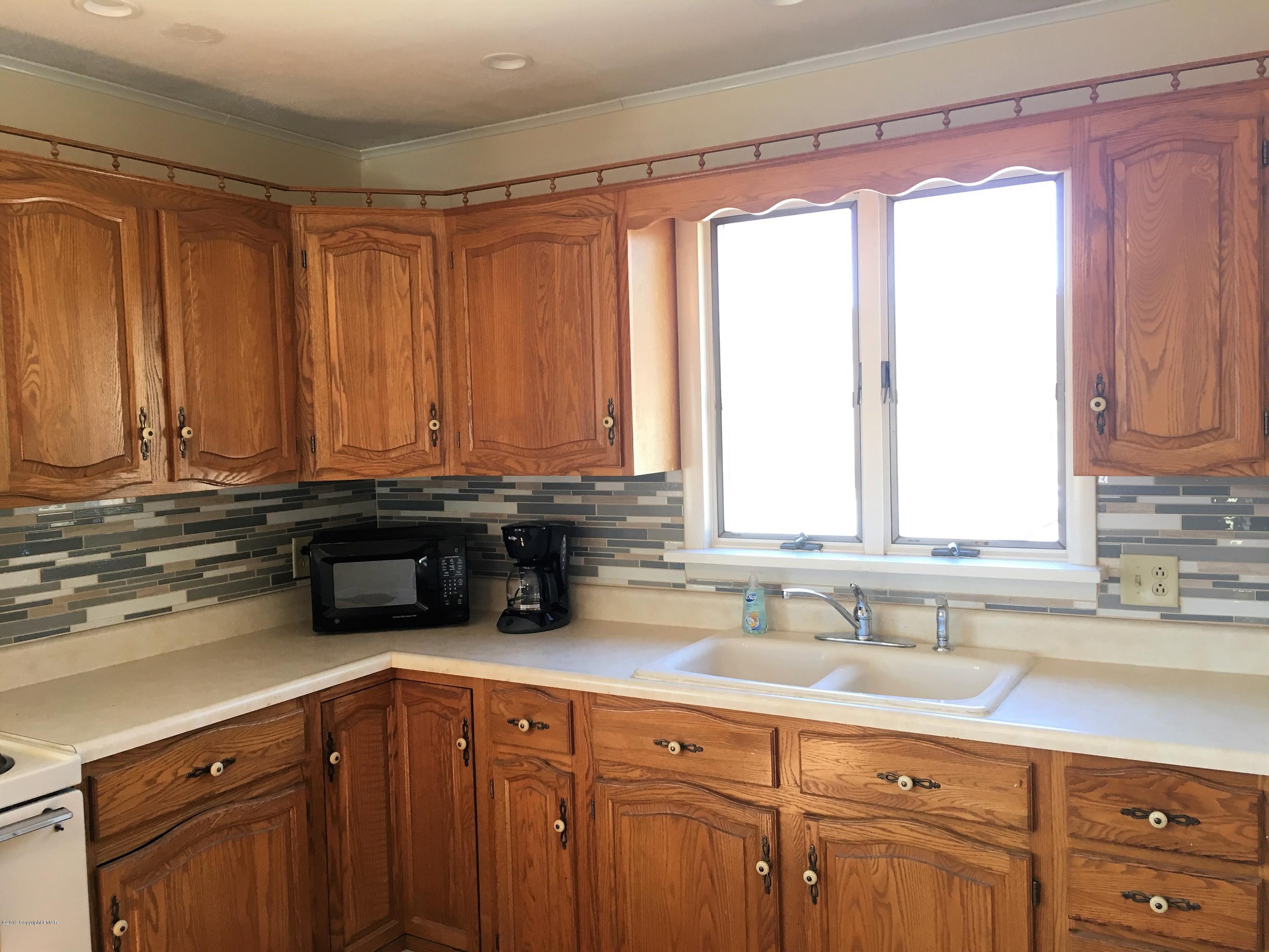 5736 Neola Road Stroudsburg, PA 18360 - Photo 7 of 37 a kitchen with stainless steel appliances wooden cabinets a sink and a window