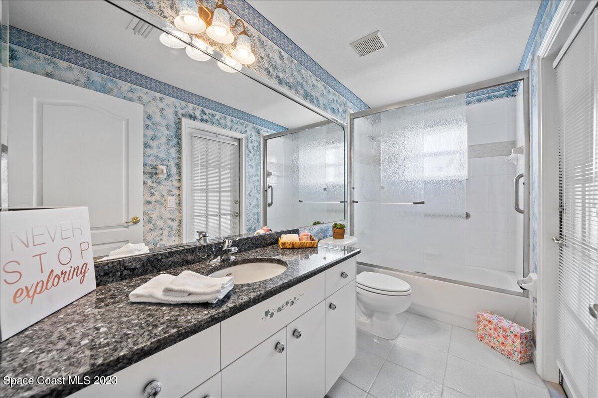 1643 Keys Gate Drive Melbourne, FL 32940 - Photo 25 of 43 a bathroom with a granite countertop sink a toilet a mirror and shower