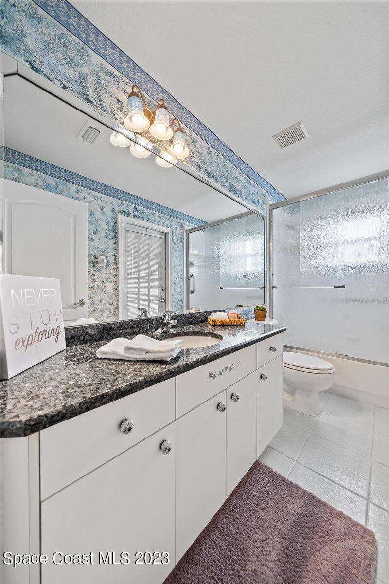 1643 Keys Gate Drive Melbourne, FL 32940 - Photo 26 of 43 a bathroom with a granite countertop sink a toilet and a mirror