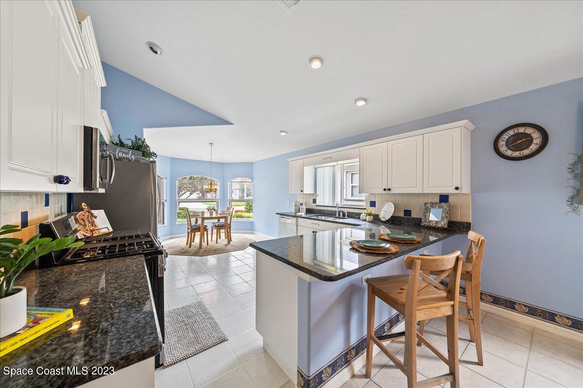 1643 Keys Gate Drive Melbourne, FL 32940 - Photo 9 of 43 a kitchen with stainless steel appliances granite countertop a sink a stove and a refrigerator