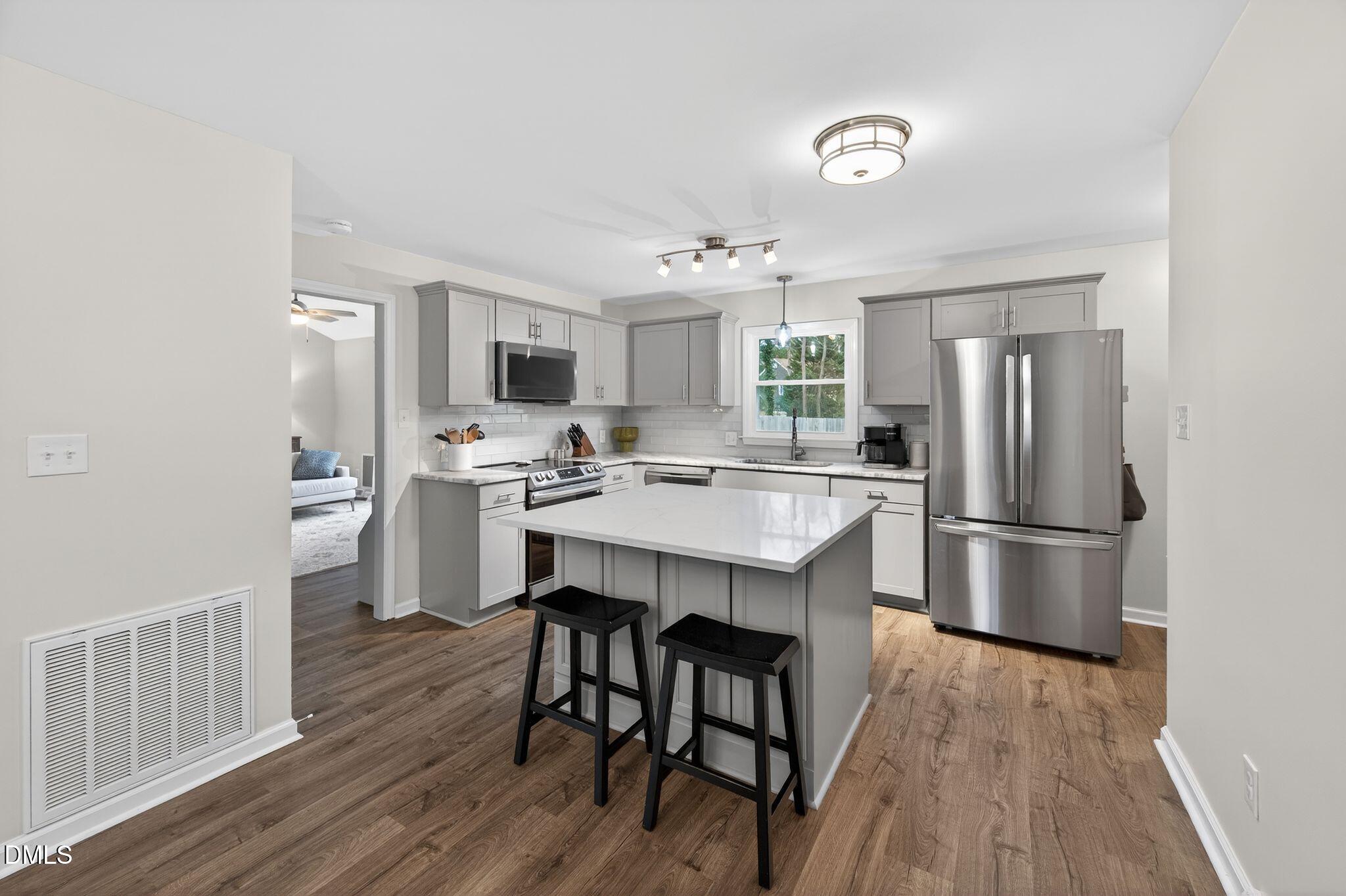 5620 Old Forge Circle Raleigh, NC 27609 - Photo 21 of 46 a kitchen with stainless steel appliances a refrigerator a stove a sink dishwasher and white cabinets with wooden floor
