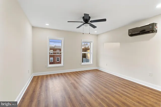 a view of empty room with wooden floor and fan