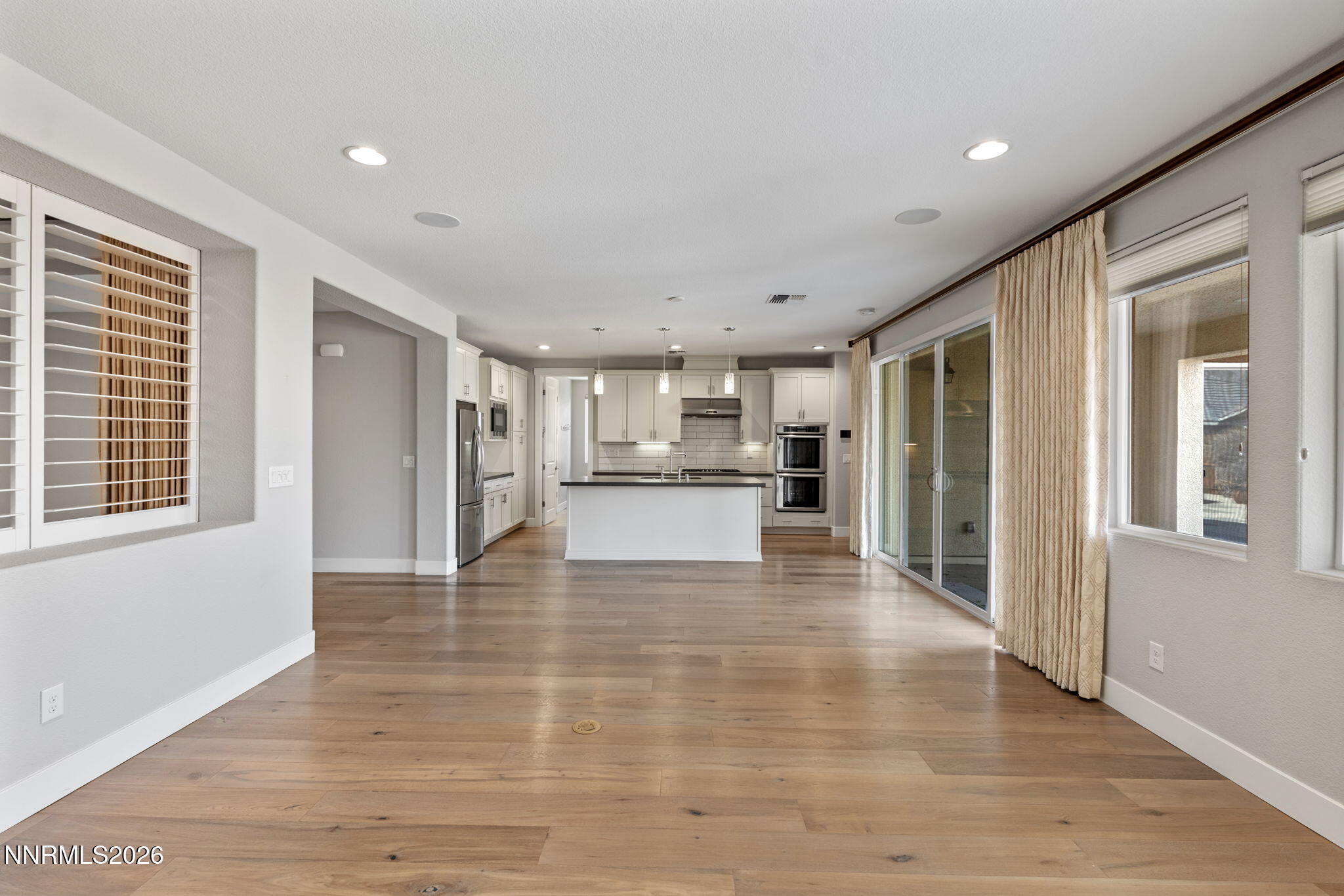 9785 Hafflinger Lane Reno, NV 89521 - Photo 12 of 34 a view of an empty room with wooden floor and a kitchen