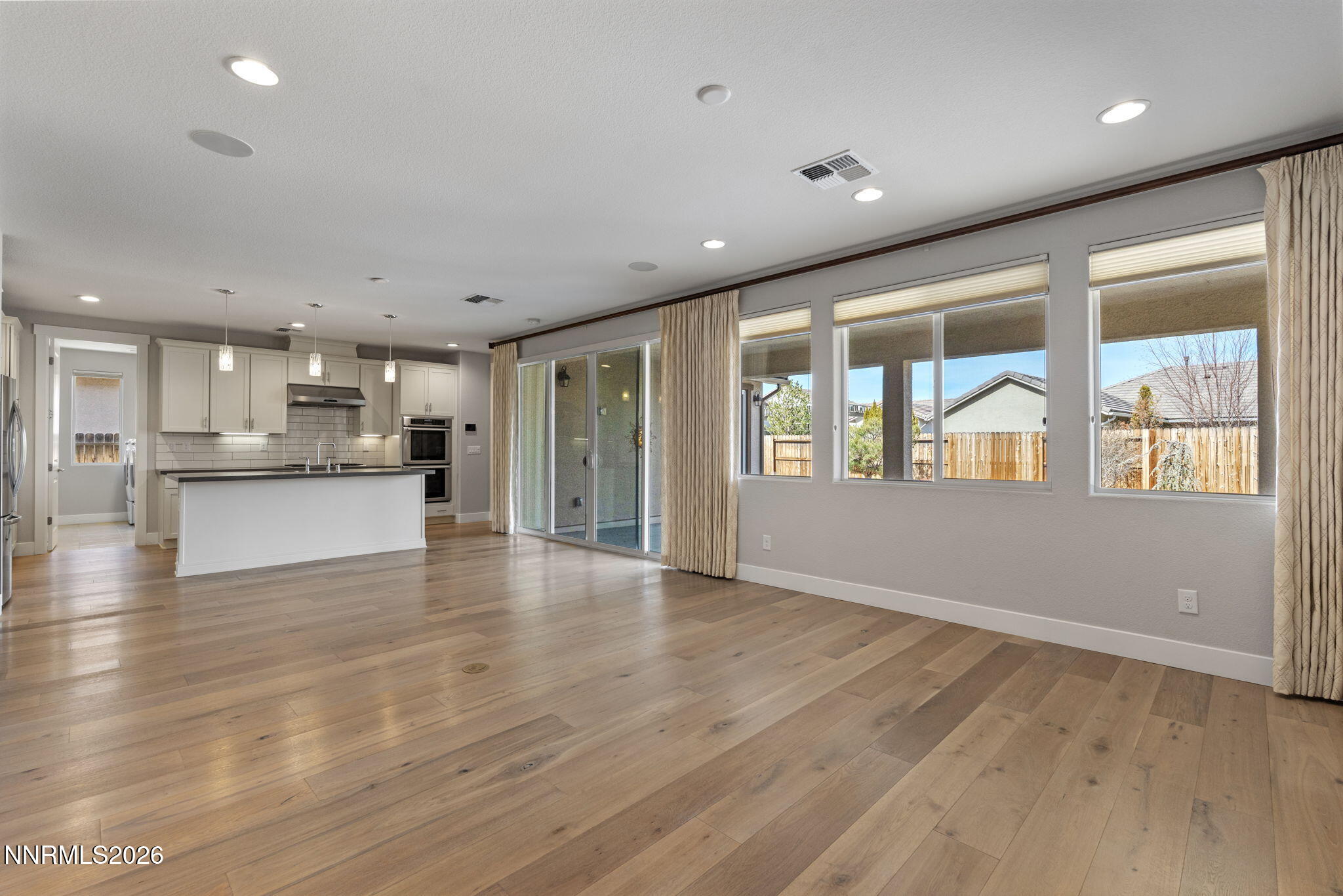 9785 Hafflinger Lane Reno, NV 89521 - Photo 13 of 34 a view of an empty room with wooden floor and a kitchen