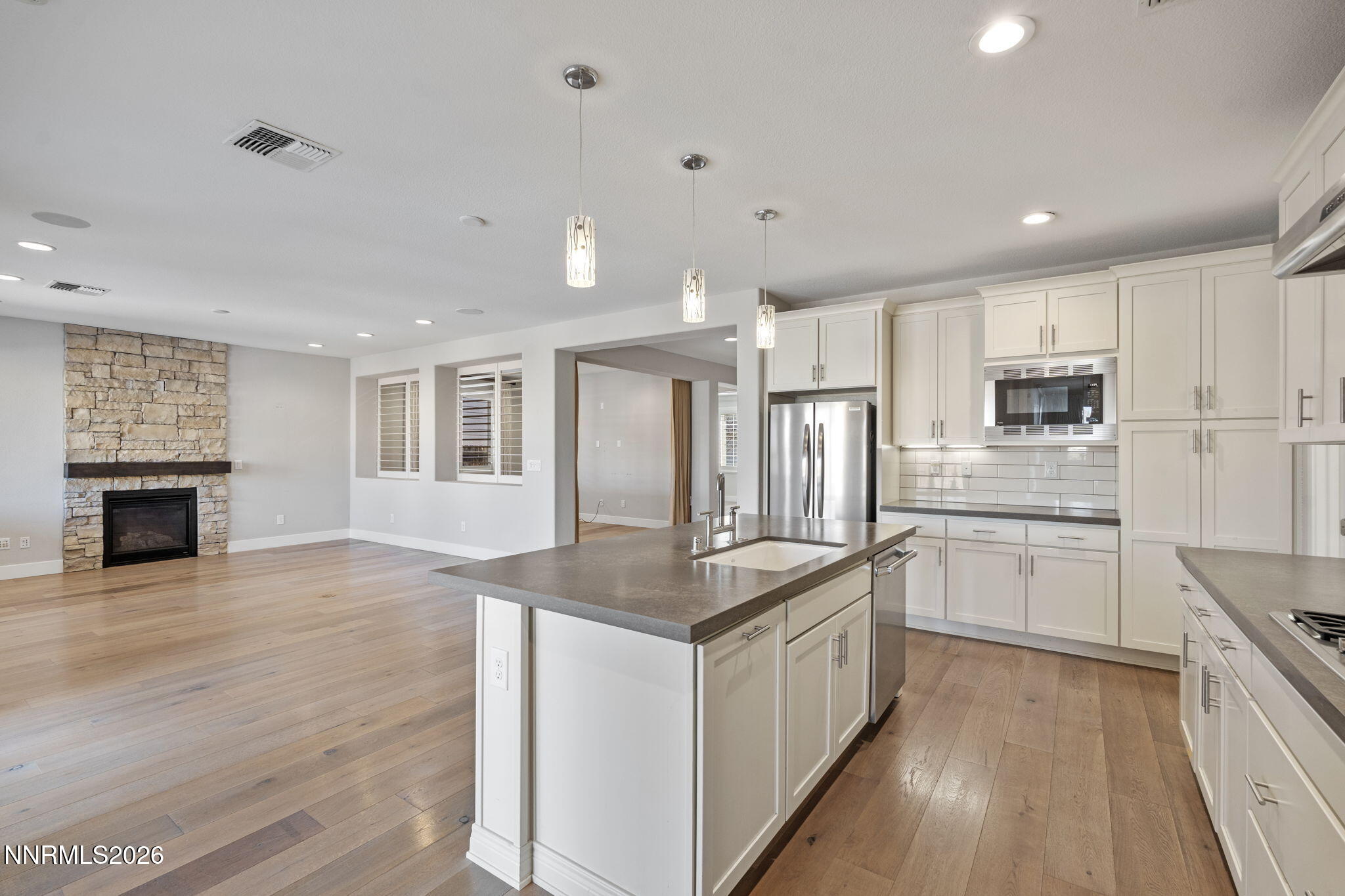 9785 Hafflinger Lane Reno, NV 89521 - Photo 15 of 34 a kitchen with stainless steel appliances granite countertop a stove top oven a sink dishwasher a refrigerator and a fireplace with wooden floor