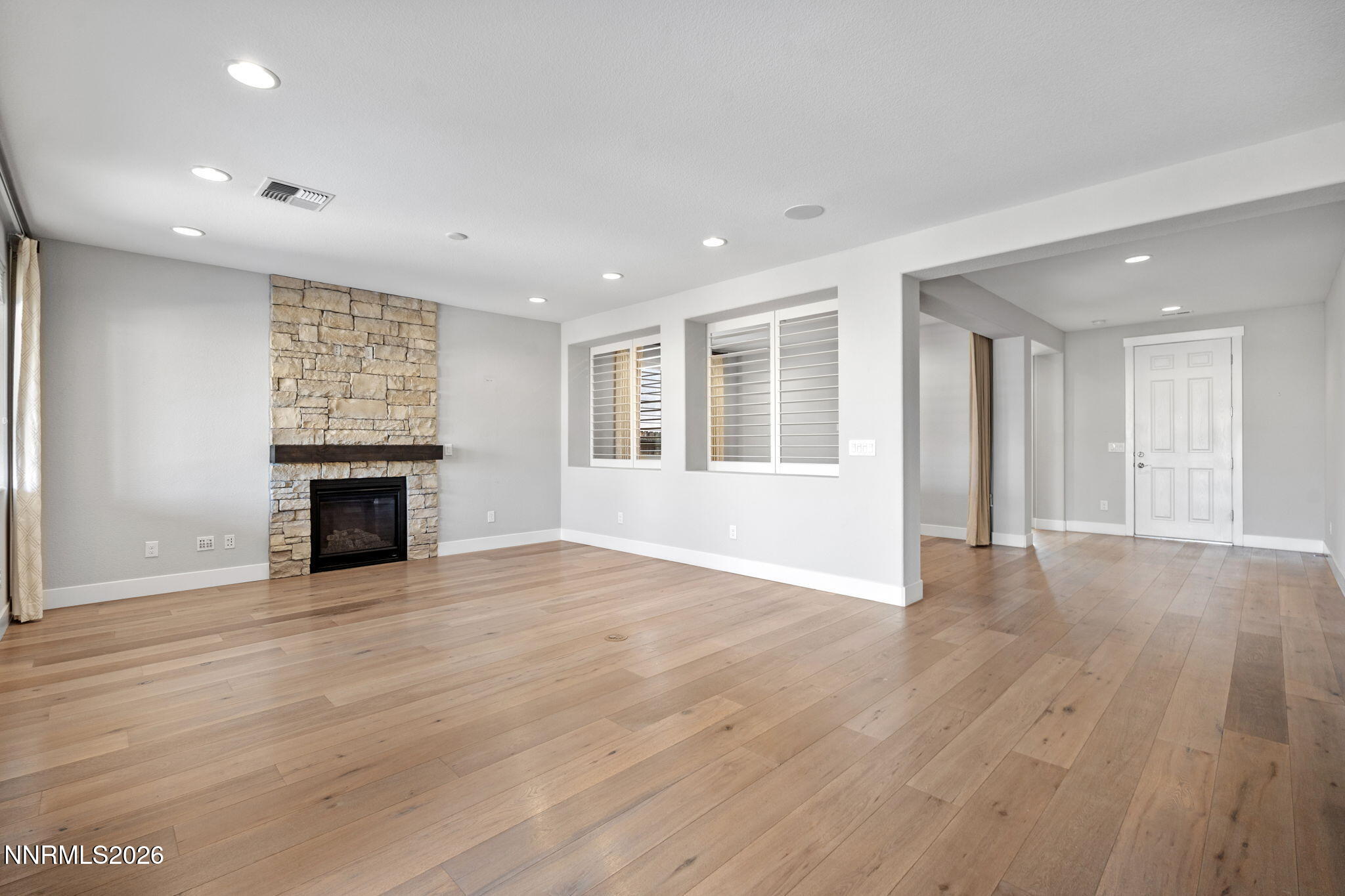 9785 Hafflinger Lane Reno, NV 89521 - Photo 8 of 34 an empty room with wooden floor fireplace and windows