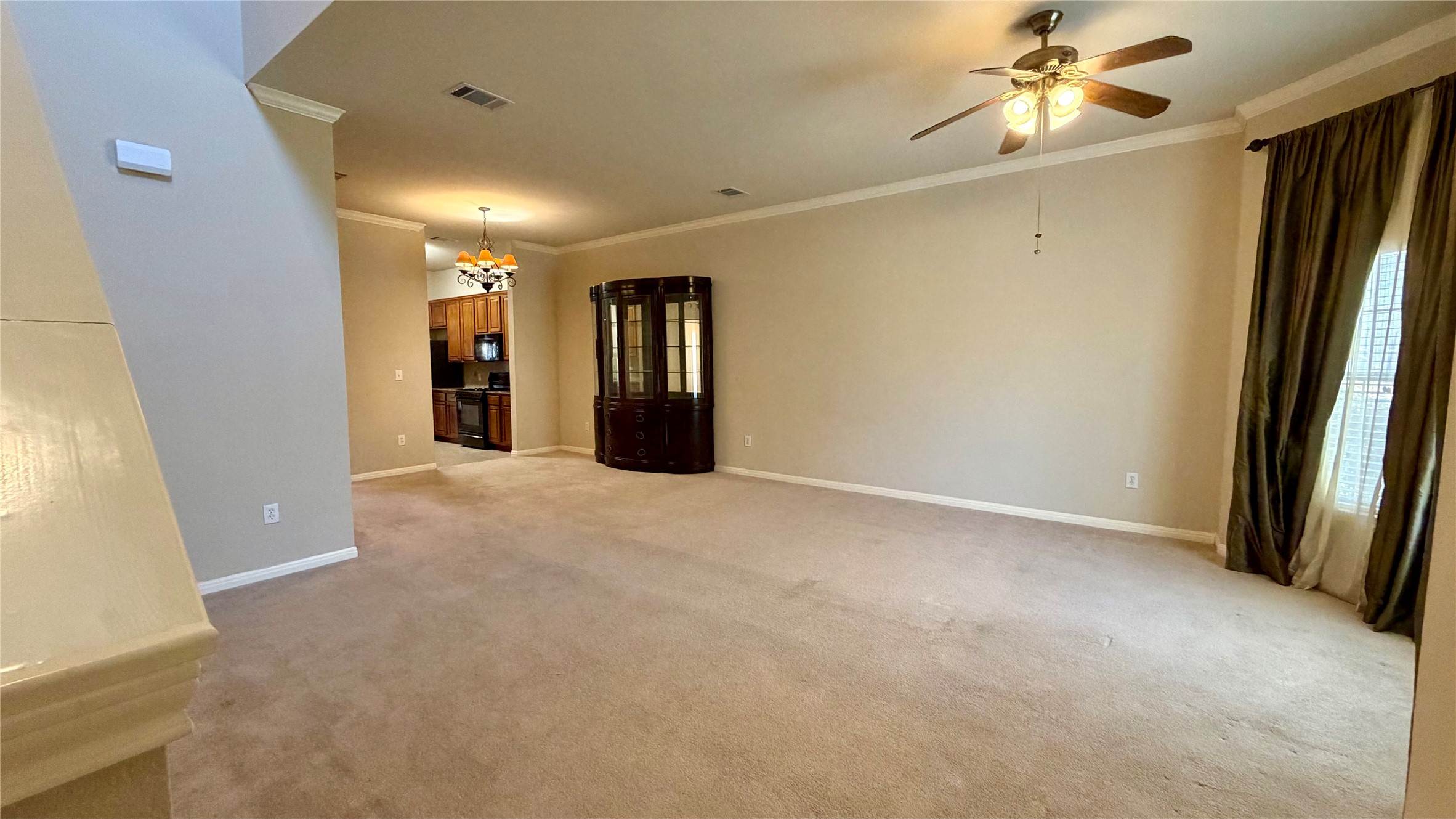 Great Room with crown molding, ceiling fan, light colored carpet, and a chandelier in dining area