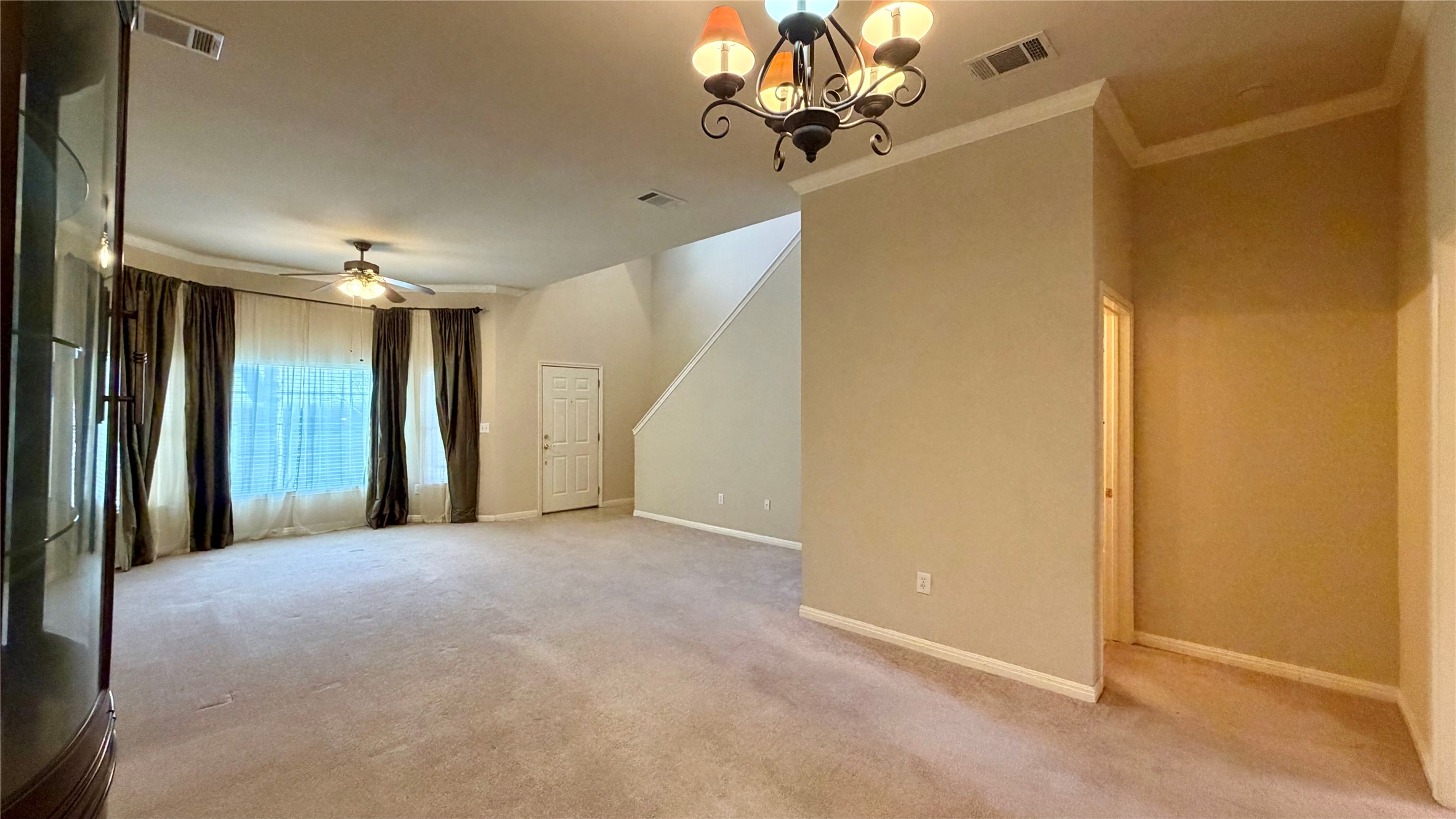 5515 Davis Lane, Unit 82 Austin, TX 78749 - Photo 3 of 28 View from Dining to Great Room featuring hanging lights, crown molding, light colored carpet, and a ceiling fan.