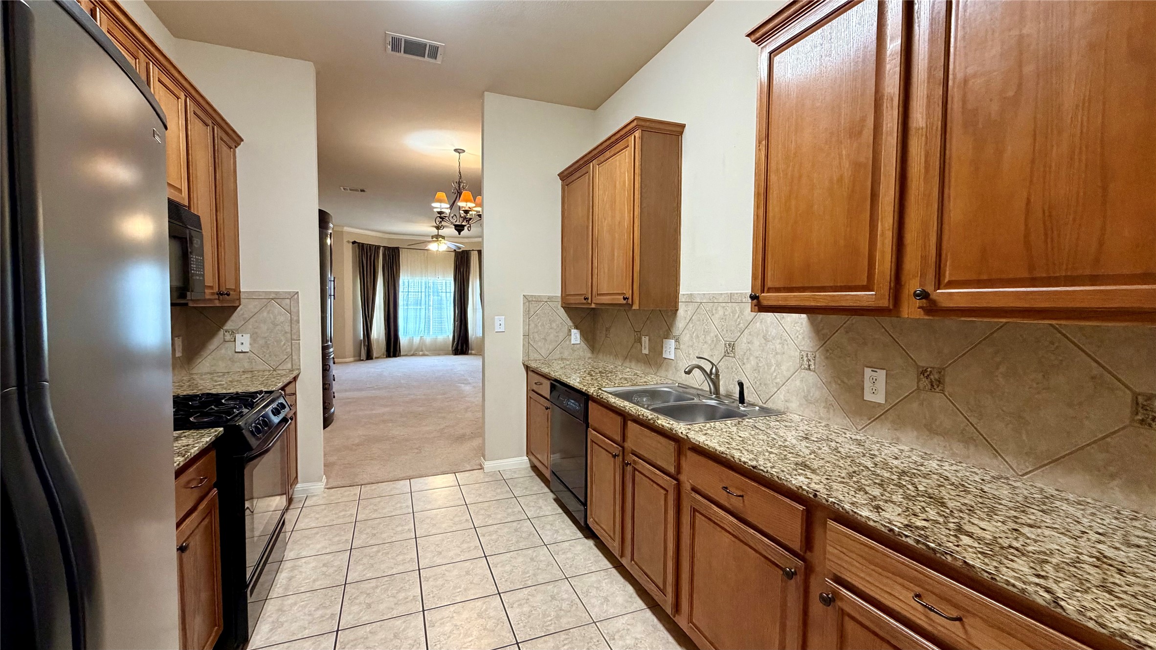 5515 Davis Lane, Unit 82 Austin, TX 78749 - Photo 6 of 28 Kitchen with black appliances, wood finish cabinetry, and granite countertops.