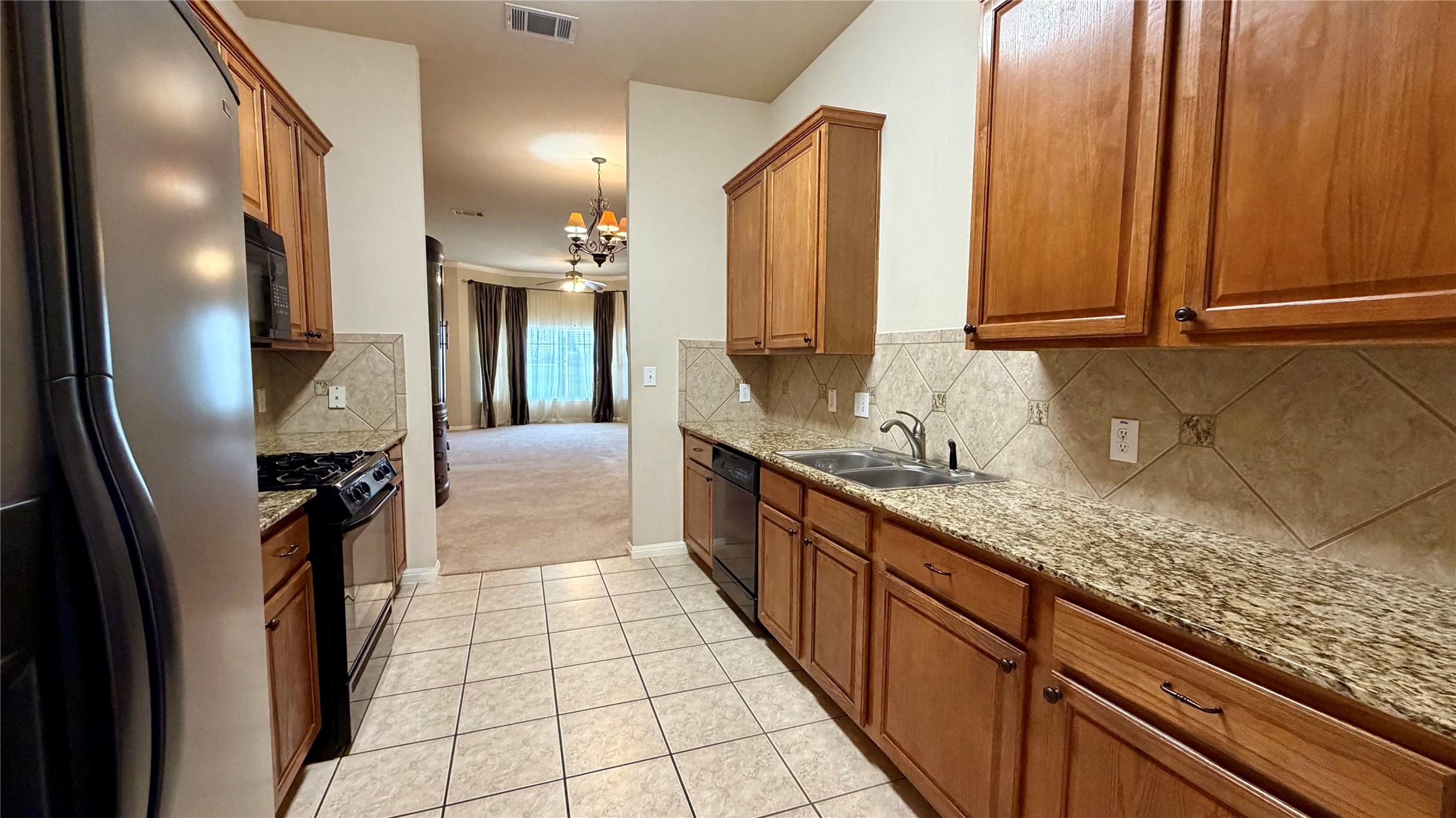 5515 Davis Lane, Unit 82 Austin, TX 78749 - Photo 7 of 28 Kitchen with black appliances, wood finish cabinetry, and granite countertops.