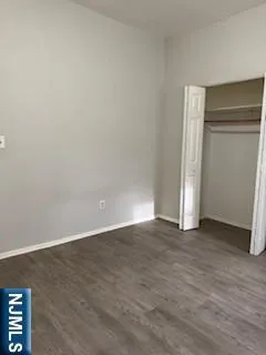 a view of an empty room with wooden floor and closet