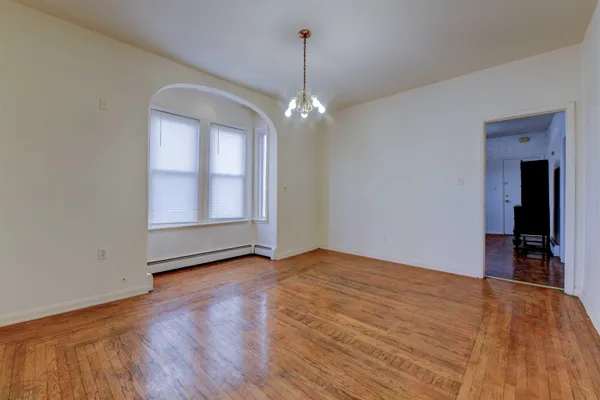a view of empty room with wooden floor and ceiling fan