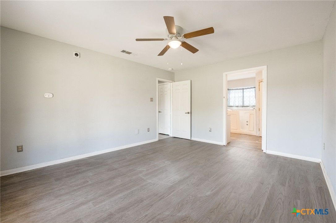 554 County Road 4707 Kempner, TX 76539 - Photo 14 of 33 an empty room with wooden floor ceiling fan and windows