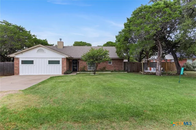 a front view of a house with a garden and trees