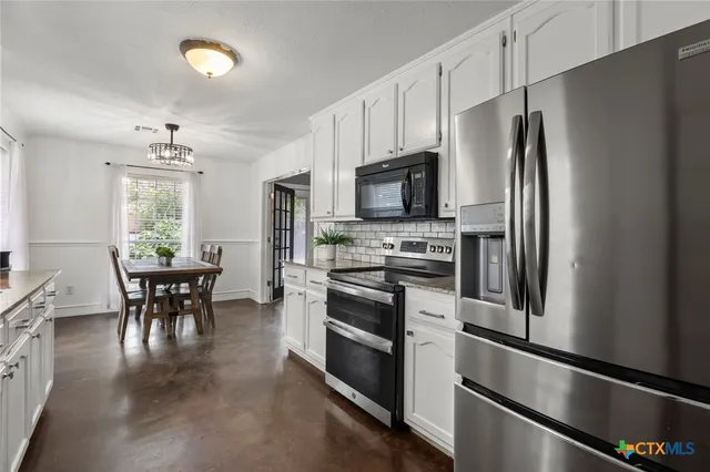 a kitchen with stainless steel appliances a refrigerator stove microwave and white cabinets