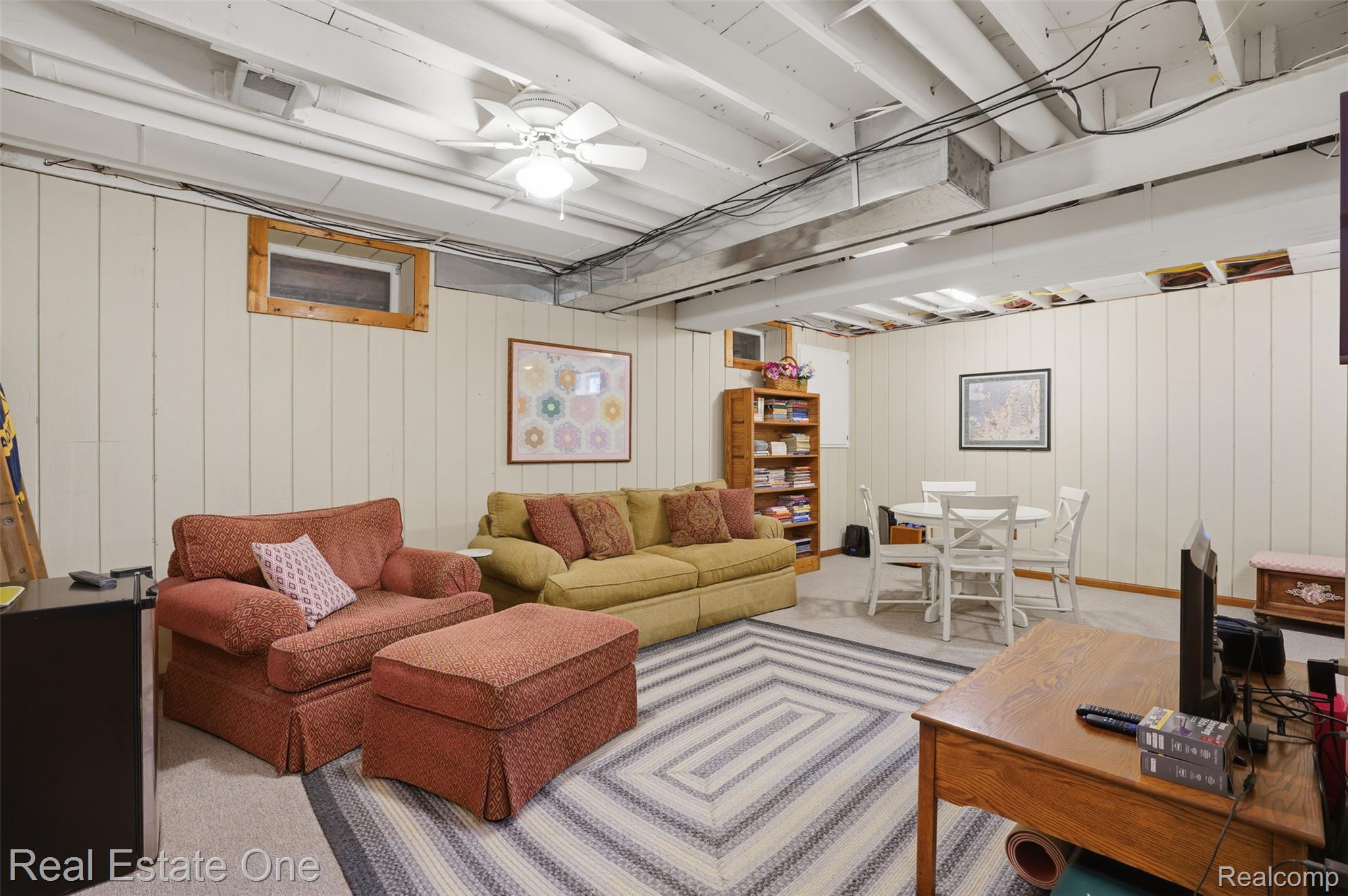 1765 Rowe Road Milford, MI 48380 - Photo 34 of 61 Finished basement area featuring paneled walls, exposed beam ceiling, recessed window, and a ceiling fan with integrated lighting