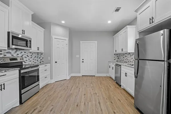 a kitchen with white cabinets stainless steel appliances and wooden floor