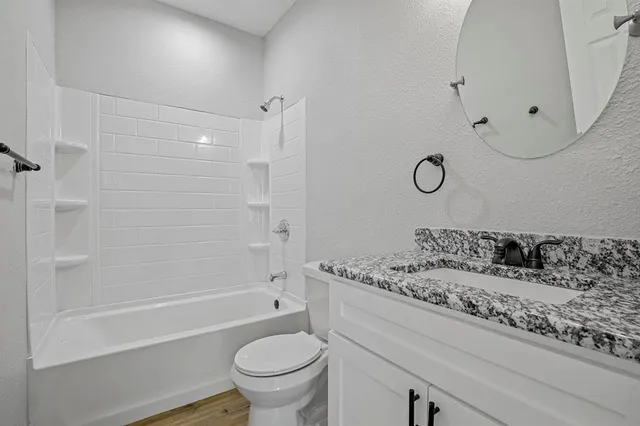 a bathroom with a granite countertop toilet sink and mirror