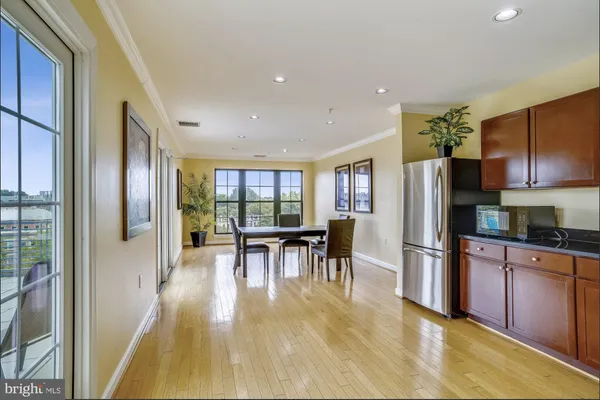 a kitchen with stainless steel appliances granite countertop a refrigerator a stove a dining table and chairs with wooden floor