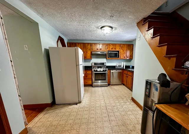 a view of kitchen with refrigerator stove and wooden floor