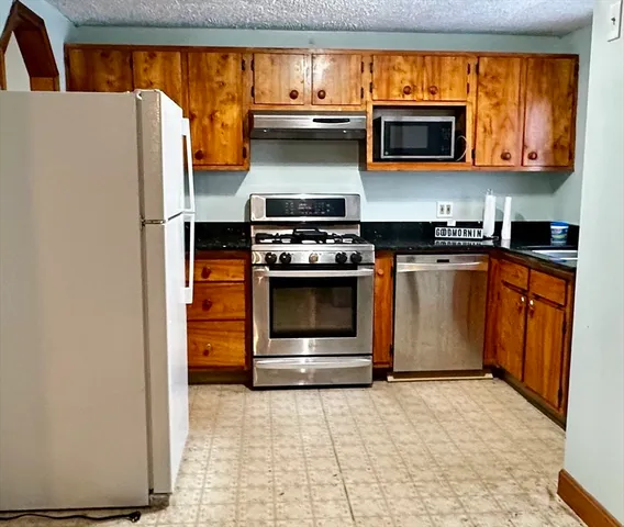 a kitchen with stainless steel appliances granite countertop a stove microwave and refrigerator