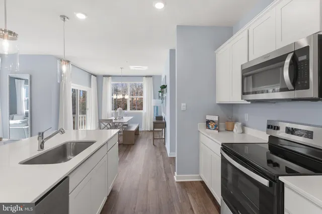 a kitchen with kitchen island a white counter top space stainless steel appliances and cabinets
