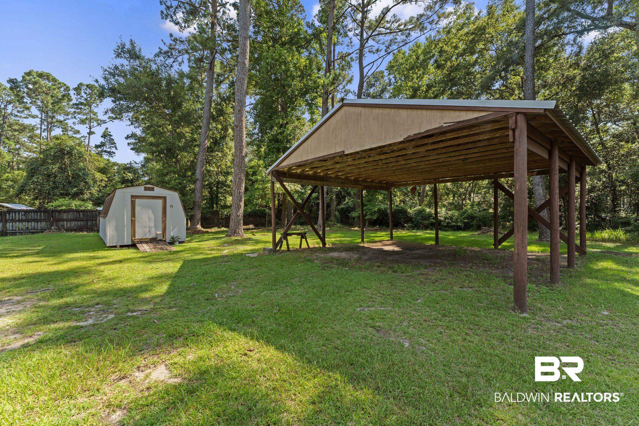 14095 Riverside Drive Foley, AL 36535 - Photo 29 of 30 View of yard featuring a storage shed, a detached carport, and view of wooded area