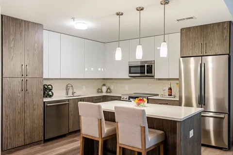 a kitchen with a sink a microwave a refrigerator and white cabinets