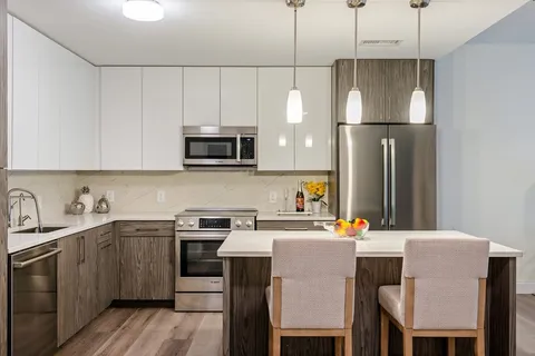 a kitchen with stainless steel appliances a stove a sink a refrigerator a microwave a dining table and chairs