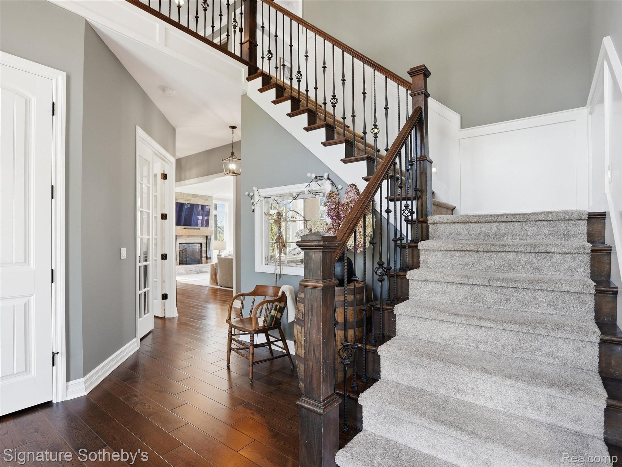 1595 Carriage Way Rochester, MI 48307 - Photo 37 of 78 Stairway with hardwood / wood-style flooring, a glass covered fireplace, and a high ceiling