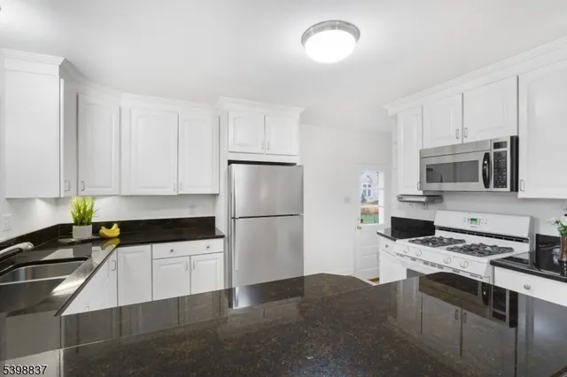 a kitchen with stainless steel appliances white cabinets and a stove top oven