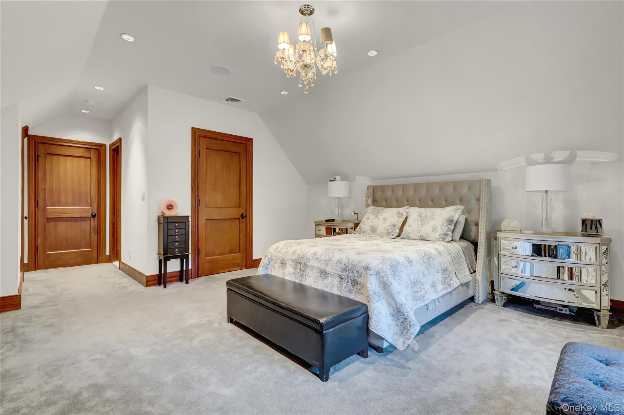 63 Dyke Road Setauket, NY 11733 - Photo 36 of 49 a spacious bedroom with a bed and a chandelier