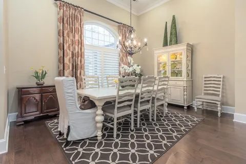 a dining room with wooden floor a chandelier a glass table and chairs