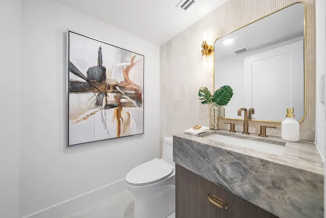 a bathroom with a granite countertop sink mirror vanity and toilet