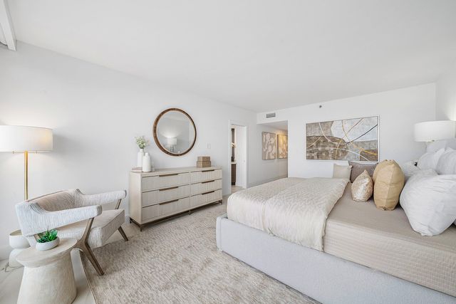 a bedroom with a bed a couch and a lamp on dresser