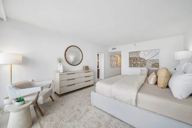 a bedroom with a bed a couch and a lamp on dresser