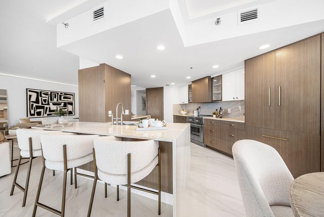 a kitchen with refrigerator a stove a sink and chairs