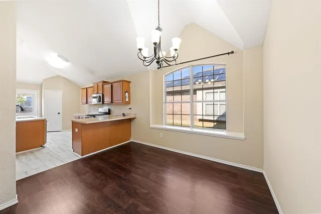 a dining room with wooden floor a chandelier a wooden table and chairs