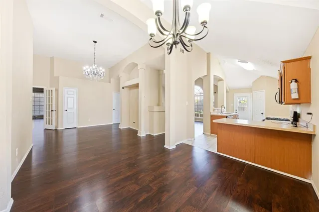a view of a room with wooden floor and kitchen view