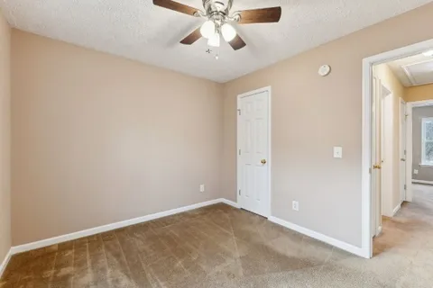 a view of an empty room and chandelier fan