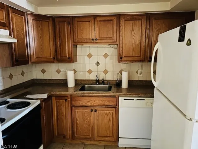 a kitchen with granite countertop wood cabinets and white appliances