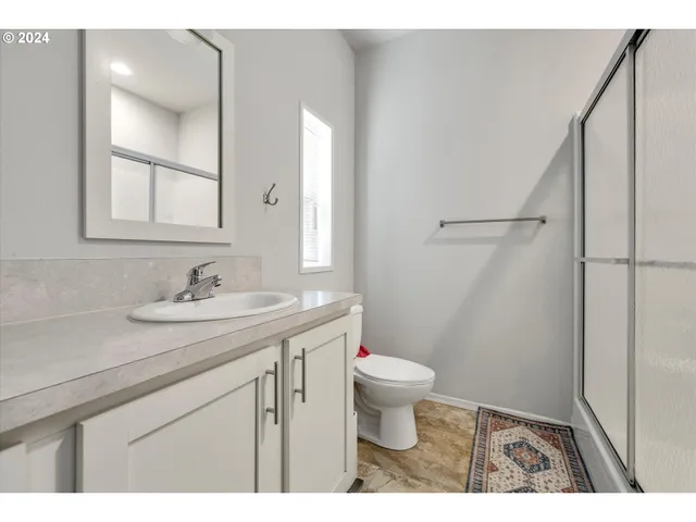 a bathroom with a sink a toilet a mirror and shower