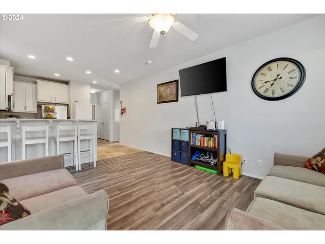 a living room with kitchen view and a wooden floor