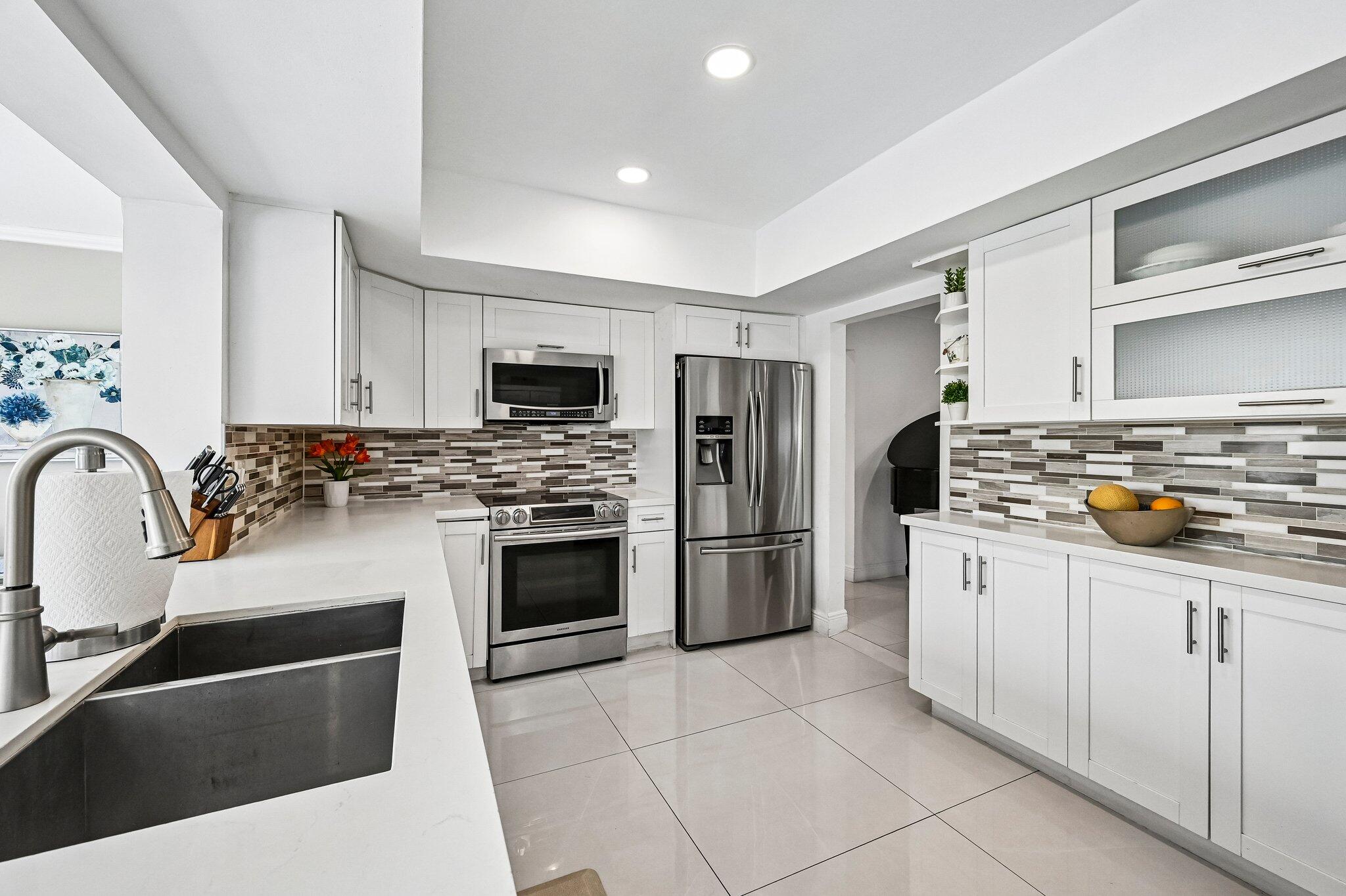 2940 Northeast 39th Court Lighthouse Point, FL 33064 - Photo 12 of 42 a kitchen with stainless steel appliances kitchen island granite countertop a sink refrigerator and cabinets